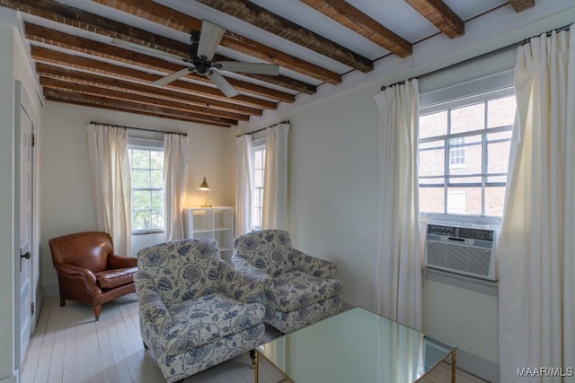 sitting room with a ceiling fan, cooling unit, beamed ceiling, and light wood-style flooring