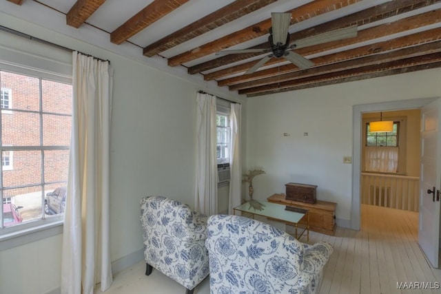 living area with light wood-style floors, beam ceiling, ceiling fan, and baseboards