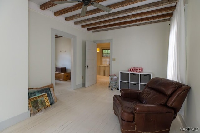 sitting room with light wood finished floors and beamed ceiling