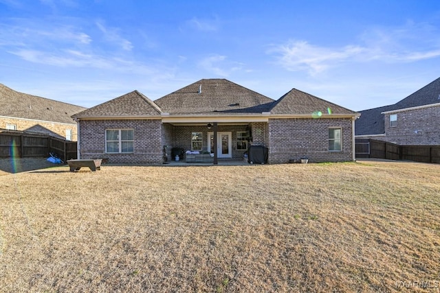 back of house featuring a yard, a fenced backyard, a patio area, and brick siding