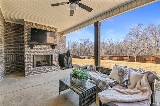 view of patio / terrace with an outdoor brick fireplace, area for grilling, a fenced backyard, and a ceiling fan