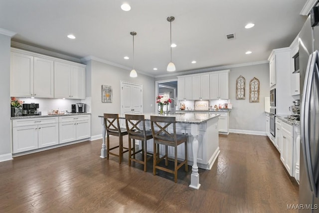 kitchen featuring light stone counters, decorative light fixtures, visible vents, appliances with stainless steel finishes, and white cabinetry