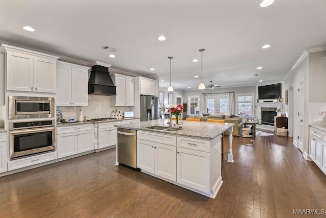 kitchen featuring white cabinetry, stainless steel appliances, a sink, and open floor plan