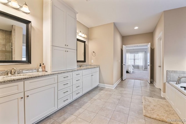 ensuite bathroom featuring double vanity, baseboards, connected bathroom, tile patterned flooring, and a sink