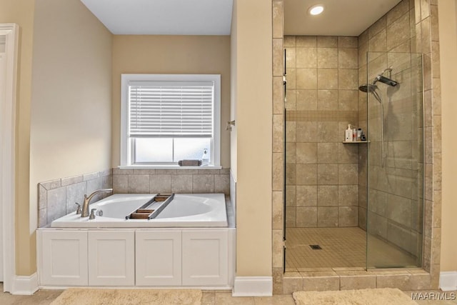 bathroom with a shower stall, baseboards, and a bath