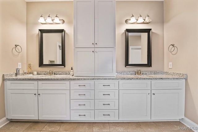 full bath featuring double vanity, a sink, and baseboards