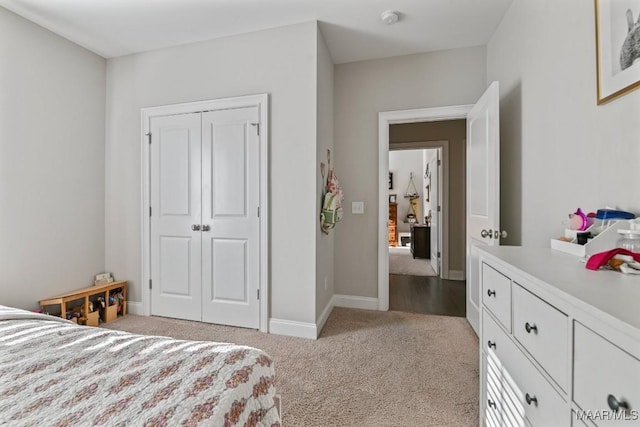 bedroom with a closet, light colored carpet, and baseboards