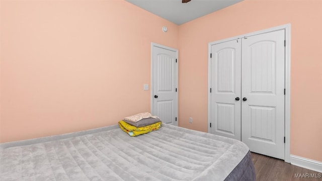 unfurnished bedroom featuring a closet, wood finished floors, a ceiling fan, and baseboards