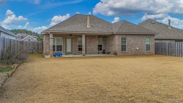 back of house featuring a fenced backyard, brick siding, roof with shingles, a lawn, and a patio area