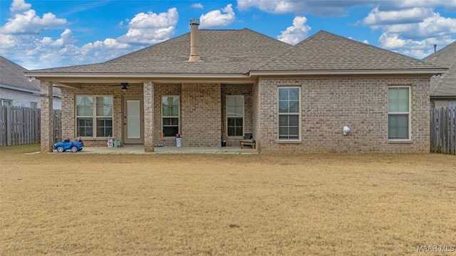 rear view of property featuring brick siding, a lawn, a patio area, and fence