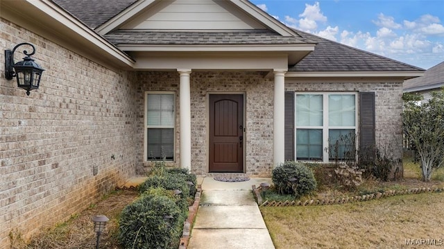 property entrance featuring brick siding and roof with shingles