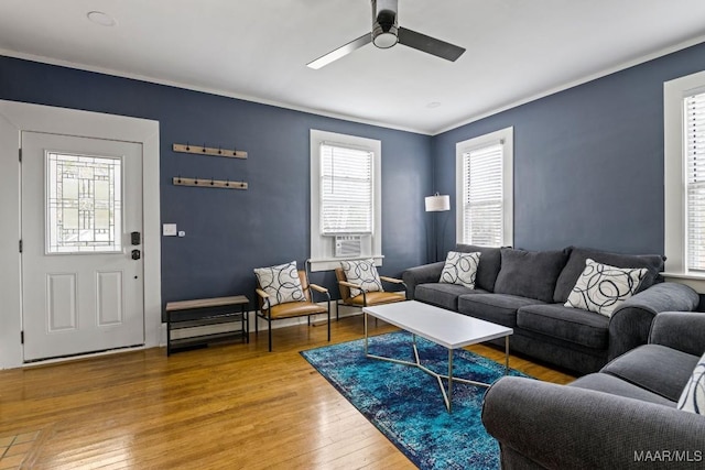 living area with a ceiling fan, wood finished floors, and ornamental molding