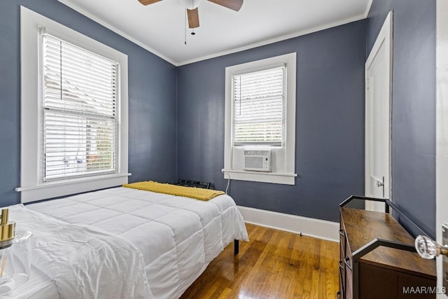 bedroom with crown molding, multiple windows, wood finished floors, and baseboards