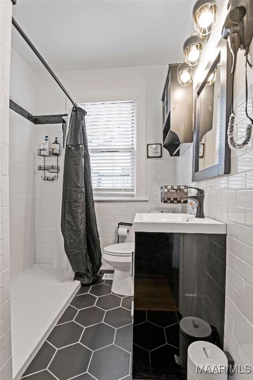 full bathroom with toilet, tile patterned flooring, vanity, a shower stall, and tile walls