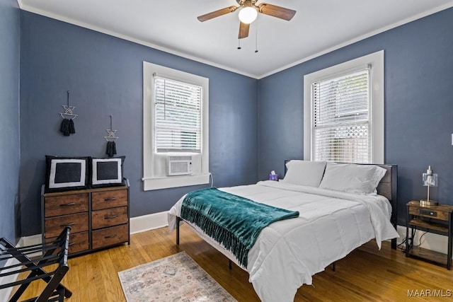 bedroom featuring light wood-style flooring, ornamental molding, a ceiling fan, cooling unit, and baseboards