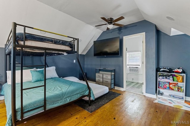 bedroom featuring lofted ceiling, connected bathroom, wood finished floors, cooling unit, and baseboards