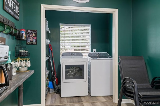 clothes washing area with laundry area, washer and clothes dryer, and wood finished floors