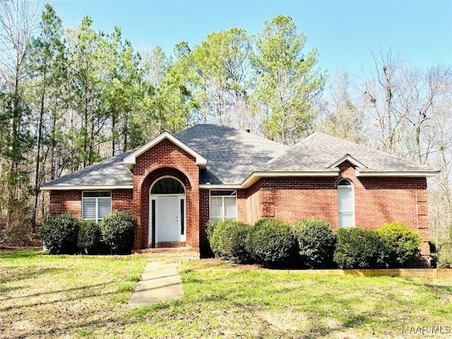 ranch-style house featuring brick siding, roof with shingles, and a front yard