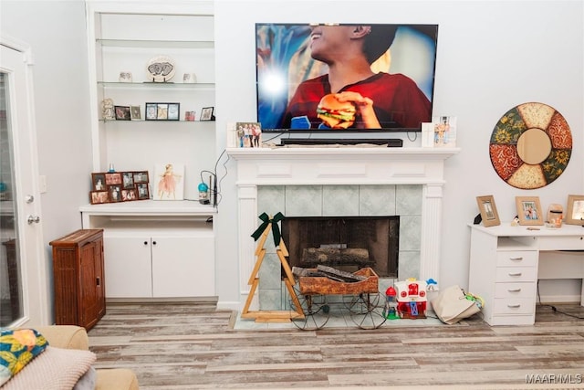 living room with light wood-style floors and a tile fireplace