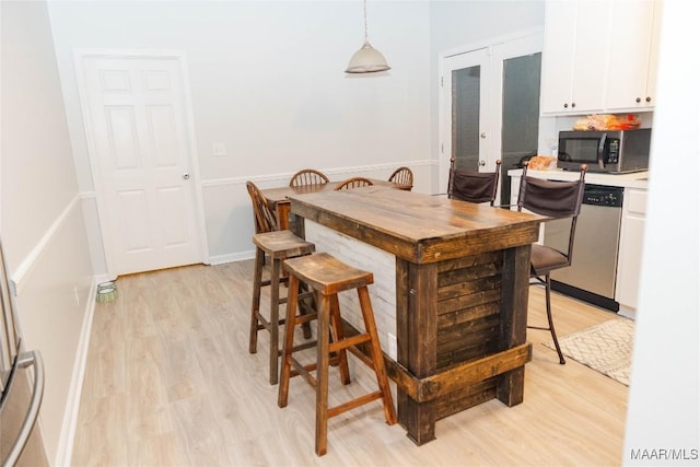 dining room with light wood-style floors, french doors, and baseboards