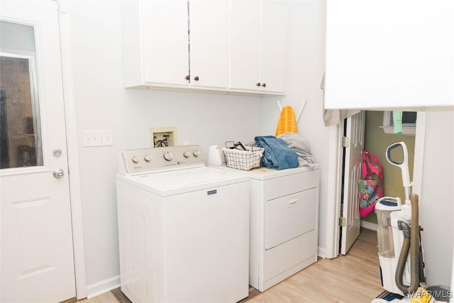 laundry area featuring separate washer and dryer, light wood-type flooring, cabinet space, and baseboards