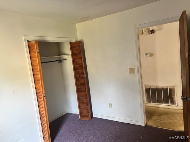 unfurnished bedroom featuring a closet, visible vents, dark carpet, and baseboards