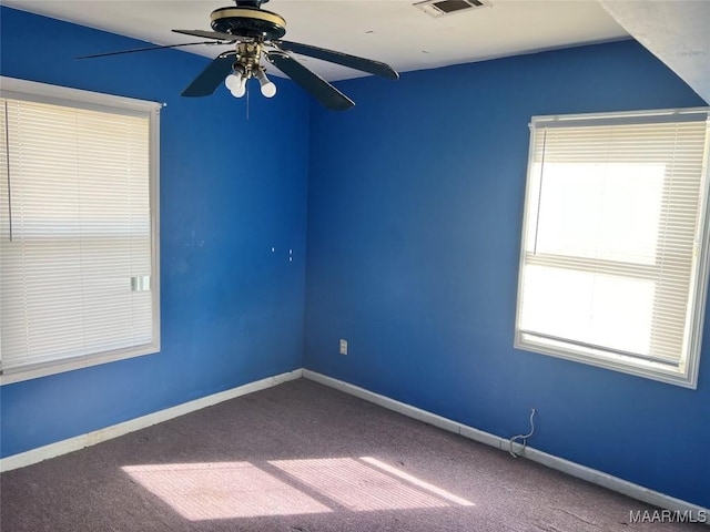 carpeted empty room with visible vents, baseboards, and a ceiling fan