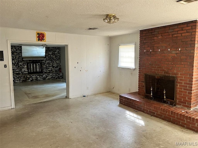 unfurnished living room featuring a textured ceiling, a fireplace, visible vents, and tile patterned floors