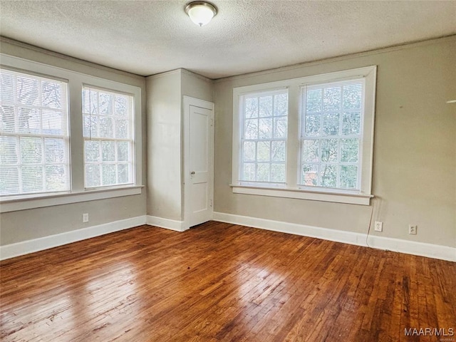 spare room featuring a textured ceiling, wood finished floors, and baseboards