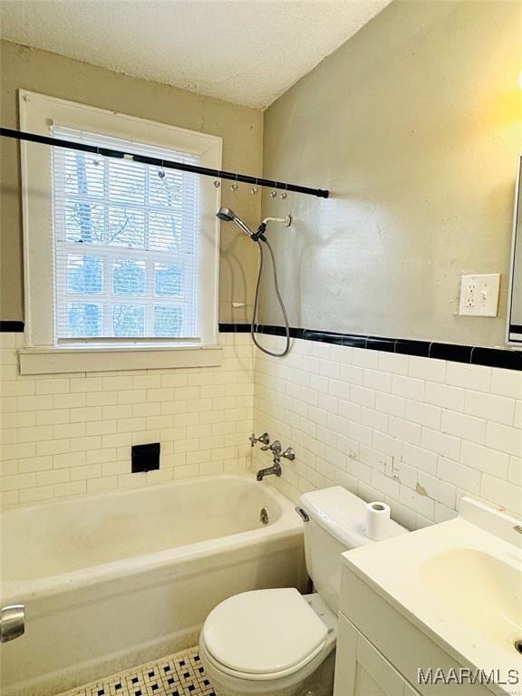 full bath featuring bathing tub / shower combination, toilet, a textured ceiling, vanity, and tile walls