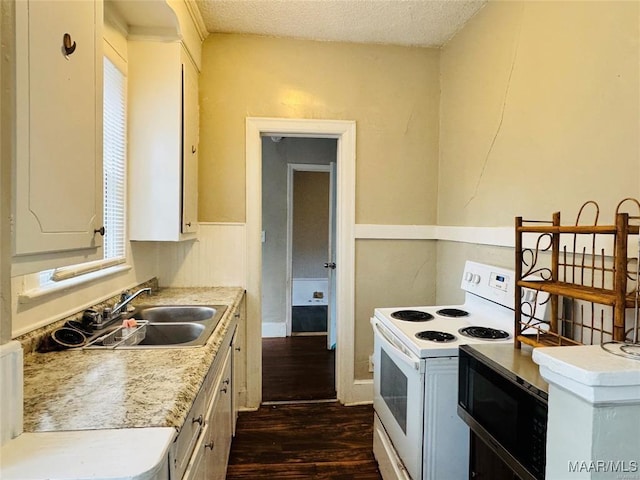 kitchen with dark wood-style flooring, light countertops, electric range, white cabinets, and a sink