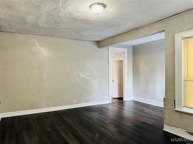 empty room featuring dark wood-style floors, baseboards, and a textured ceiling