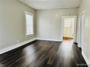 unfurnished room with dark wood-style floors and baseboards