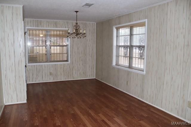 unfurnished dining area featuring dark wood-type flooring, visible vents, and an inviting chandelier