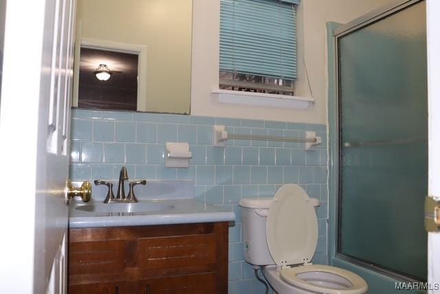 full bathroom with toilet, bath / shower combo with glass door, vanity, tile walls, and wainscoting