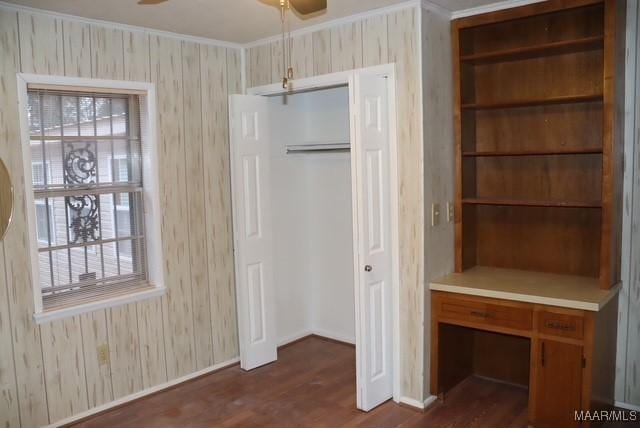 interior space featuring crown molding, baseboards, dark wood finished floors, and a closet