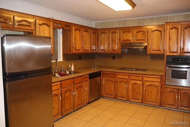 kitchen with brown cabinets, appliances with stainless steel finishes, a sink, and under cabinet range hood