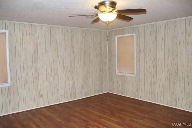 unfurnished room with a ceiling fan, dark wood-type flooring, and ornamental molding