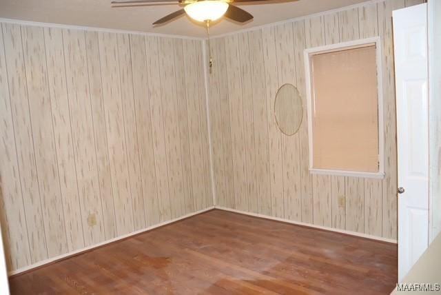 spare room with baseboards, dark wood-style flooring, a ceiling fan, and crown molding