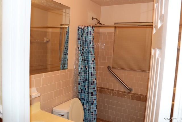 full bath with toilet and tiled shower