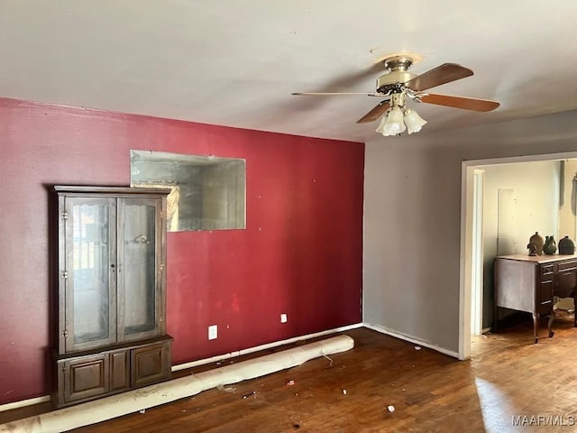 unfurnished room featuring ceiling fan, wood finished floors, and baseboards