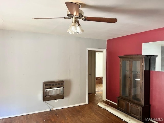 unfurnished room with baseboards, dark wood finished floors, a ceiling fan, and heating unit