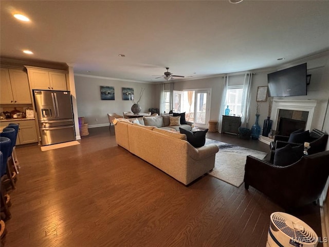 living area with dark wood-style flooring, a fireplace, crown molding, recessed lighting, and baseboards