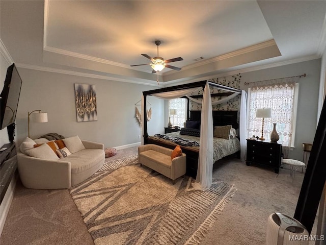 carpeted bedroom with baseboards, visible vents, a ceiling fan, ornamental molding, and a tray ceiling