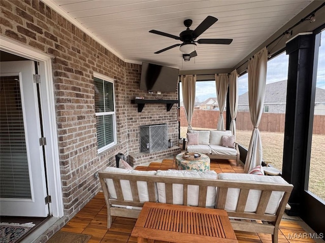 sunroom featuring a ceiling fan and a brick fireplace