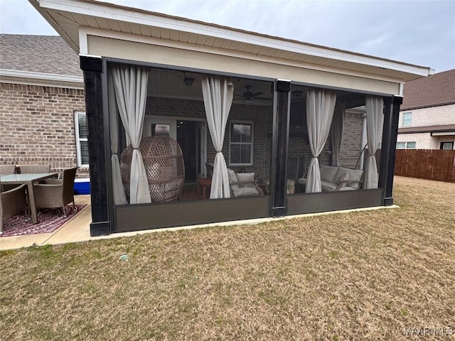 rear view of property with a yard, brick siding, fence, and a sunroom