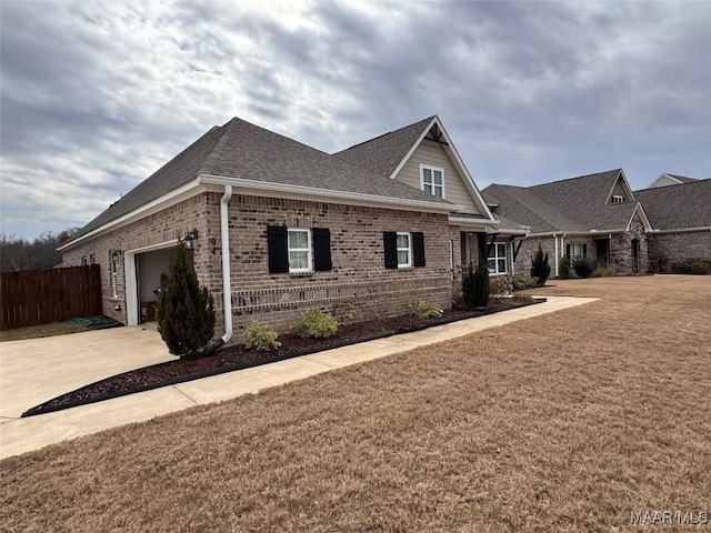 view of front facade featuring a shingled roof, concrete driveway, fence, a front lawn, and brick siding