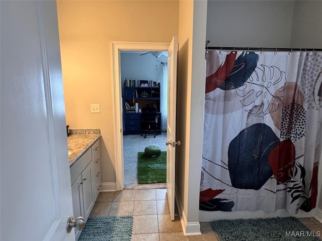 full bath featuring curtained shower, tile patterned flooring, baseboards, and vanity