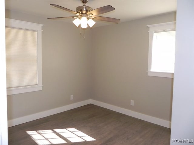 unfurnished room featuring dark wood-style flooring, a ceiling fan, and baseboards