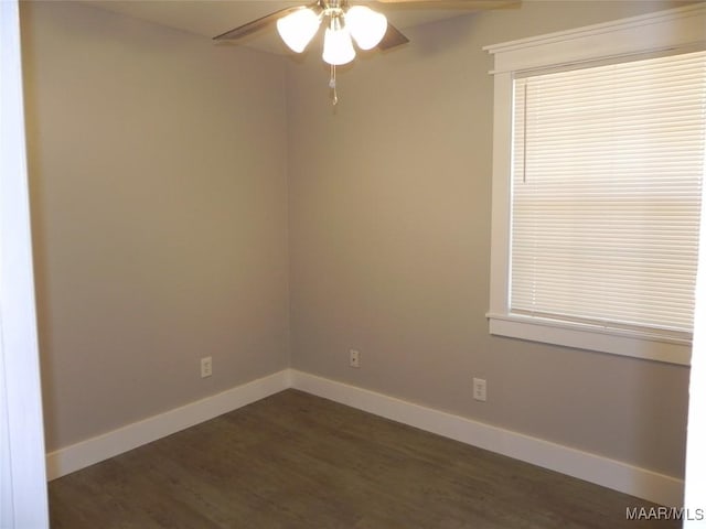 spare room featuring dark wood-style floors, a ceiling fan, and baseboards